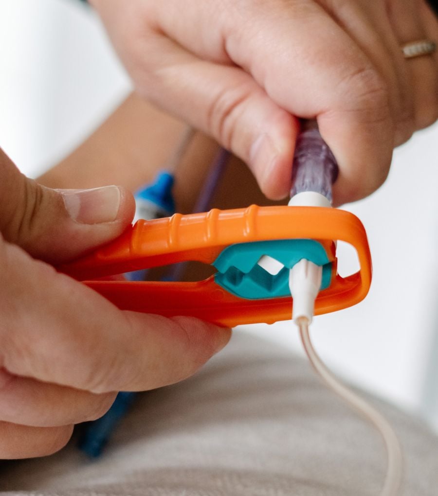 Hands using an orange Yewtwist to twist apart an IV connection
